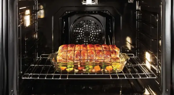 Ein Braten mit Gemüse gart in einem Glasbehälter im Ofen. Perfekt für **niedertemperatur garen** für zartes Fleisch und saftiges Gemüse.