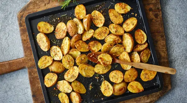 Goldbraune, knusprige Kartoffelspalten mit Rosmarin und Knoblauch, bereit für ein köstliches Ofenkartoffeln Rezept.