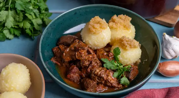 Herzhaftes Gulasch mit Klößen, ein klassisches Gulasch Rezept, garniert mit Petersilie.