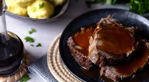 Zartes Fleisch in dunkler Sauce, perfekt für ein klassisches Sauerbraten Rezept. Dazu Klöße und frische Petersilie.