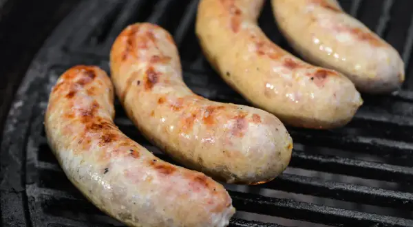 Drei goldbraune Bratwürste brutzeln auf dem Grill. Perfekt für alle, die Bratwurst selber machen wollen.