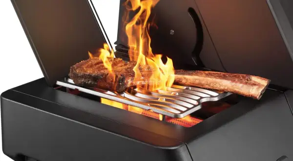 Zwei saftige Steaks brutzeln in der Sizzle Zone des Grills, umgeben von lodernden Flammen.