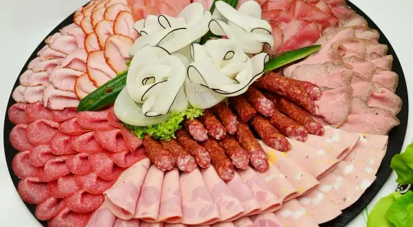 Eine reichhaltige Auswahl an Wurst Sorten, kunstvoll arrangiert auf einer Platte. Verschiedene Schinken-, Salami- und Brühwurst-Varianten laden zum Genuss ein.