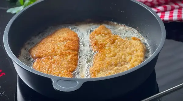 Zwei panierte Schnitzel braten in heißem Öl. Die goldbraune Kruste verspricht ein perfektes Ergebnis.