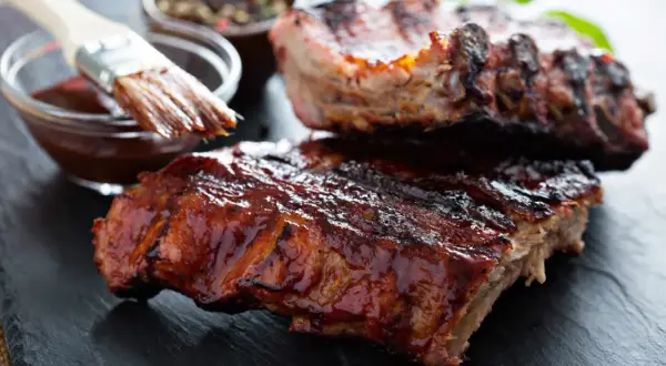 Saftige Spareribs mit glänzender BBQ-Sauce, bereit zum Servieren. Die Kerntemperatur ist perfekt für zartes Fleisch.