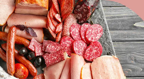Eine Auswahl an Wurstwaren: Salamischeiben, Kochschinken, Bratwürste und Speck. Die Vielfalt zeigt die **Definition Wurst** in ihrer ganzen Pracht.