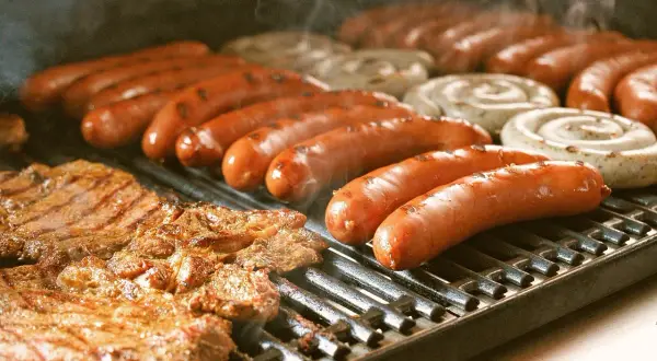 Bratwurst und Rostbratwurst brutzeln auf dem Grill. Ein kulinarischer Unterschied, der auf dem Rost sichtbar wird.