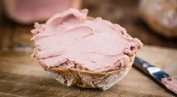 Ein Brötchen mit leckerer Leberwurst bestrichen. Ob Leberwurst gesund ist, hängt von der Zubereitung ab.