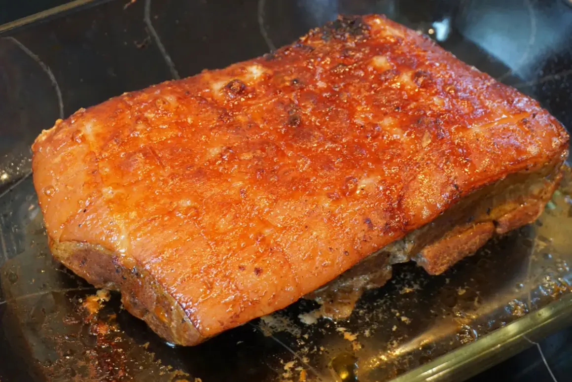 Saftiger Schweinebraten sous vide mit knuspriger Kruste, glänzend und goldbraun, ruht in einer Glasschale.