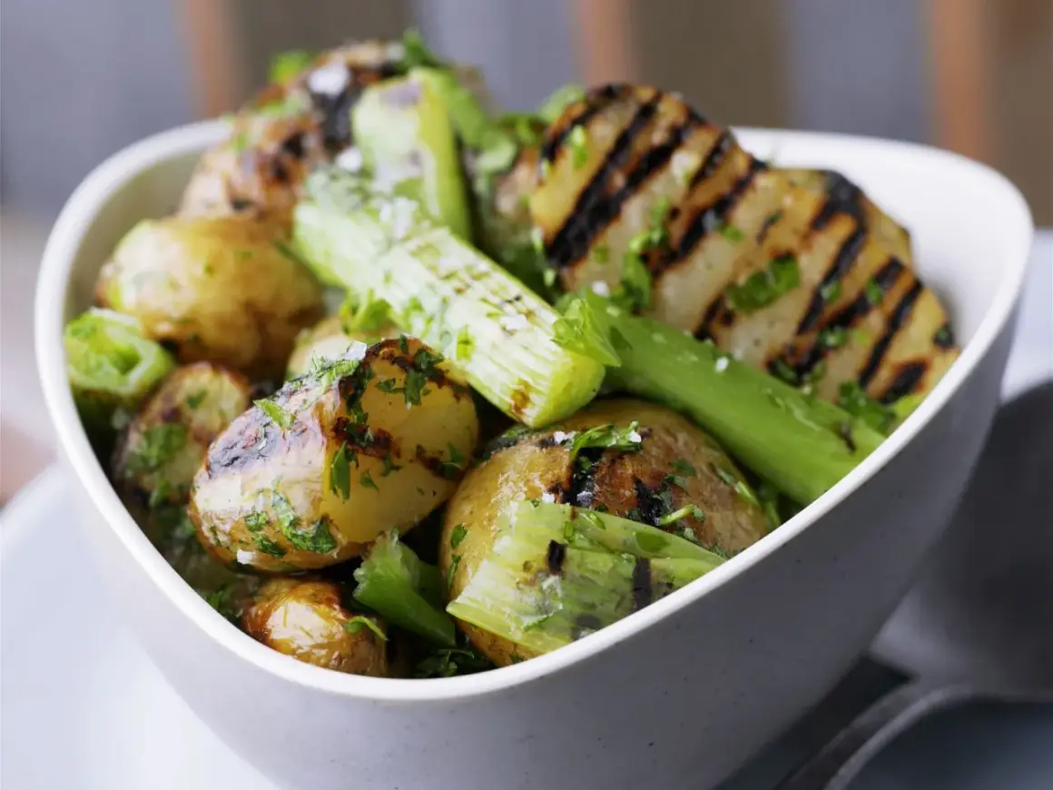 Schmackhaftes Gericht mit gegrillten Kartoffeln und Sellerie, garniert mit frischer Petersilie und grobem Salz. Perfekt für den Sommer.