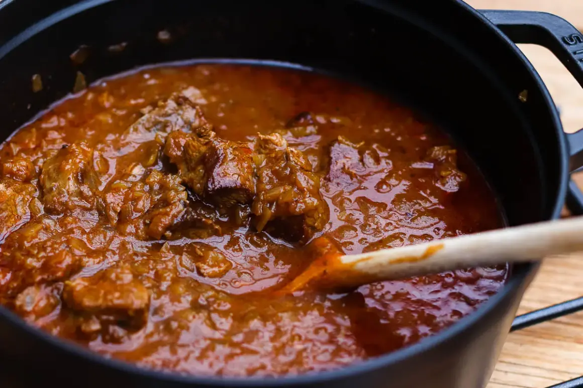 Ein dampfender Topf mit original Wiener Saftgulasch ohne Anbraten. Zarte Fleischstücke in einer würzigen Sauce, bereit zum Servieren.