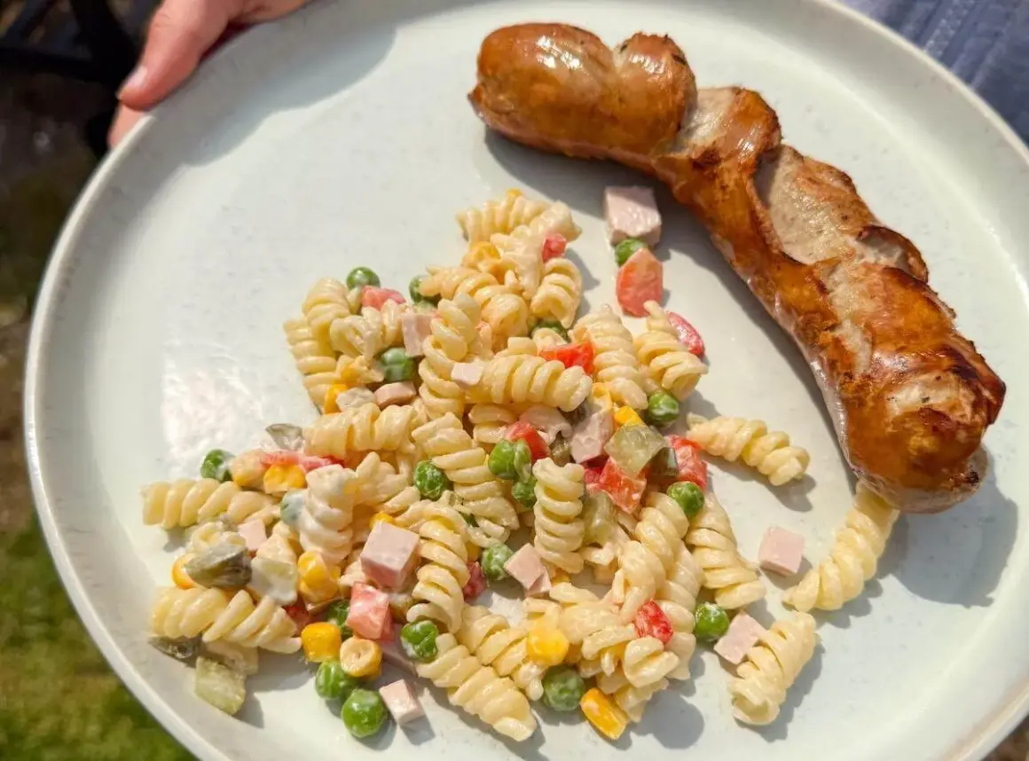 Ein herzhafter Nudelsalat mit Erbsen, Mais und Schinken, dazu eine goldbraune Bratwurst – perfekt, was passt zu Nudelsalat!