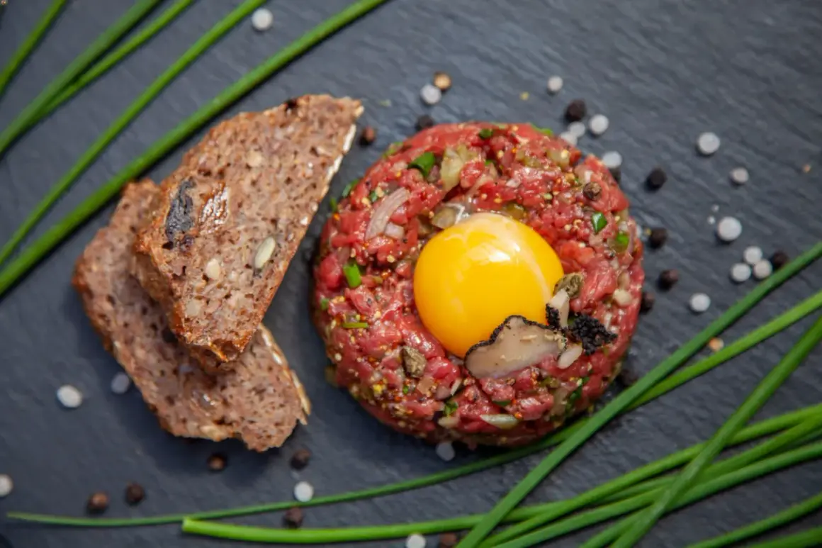 Beef Tatar mit rohem Ei, Trüffel und Brot.