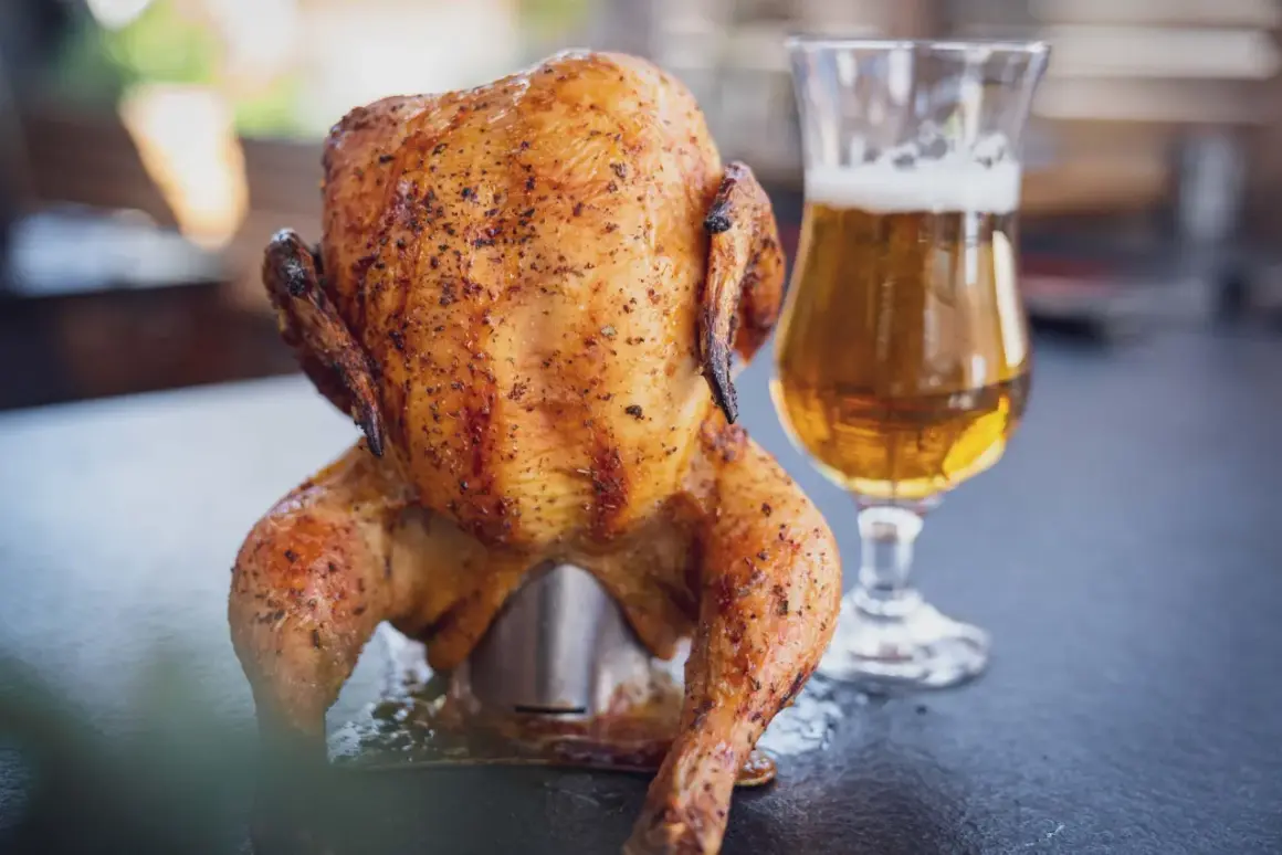Ein goldbraunes Bierdosenhähnchen, saftig und gewürzt, steht neben einem Glas Bier.