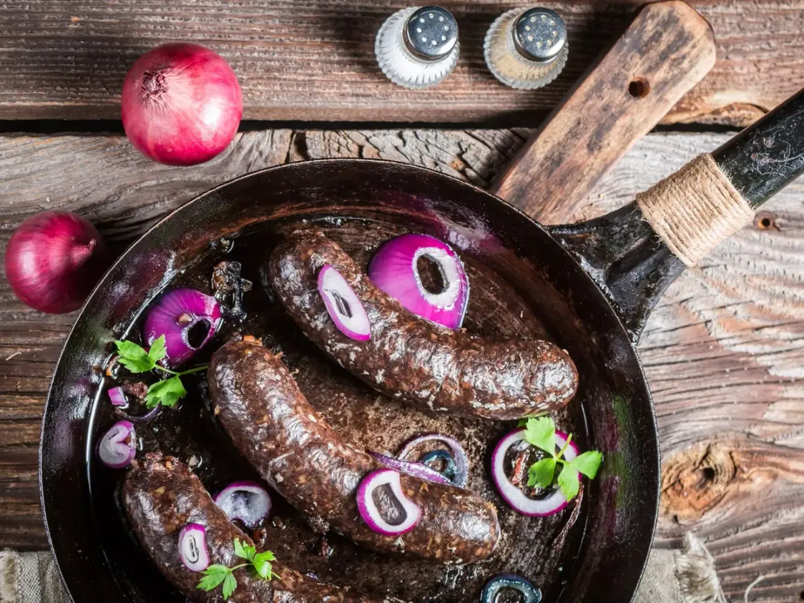 Bratwürste in der Pfanne mit Zwiebeln und Petersilie. Was ist Black Pudding? Eine herzhafte Wurstspezialität, die hier gebraten wird.