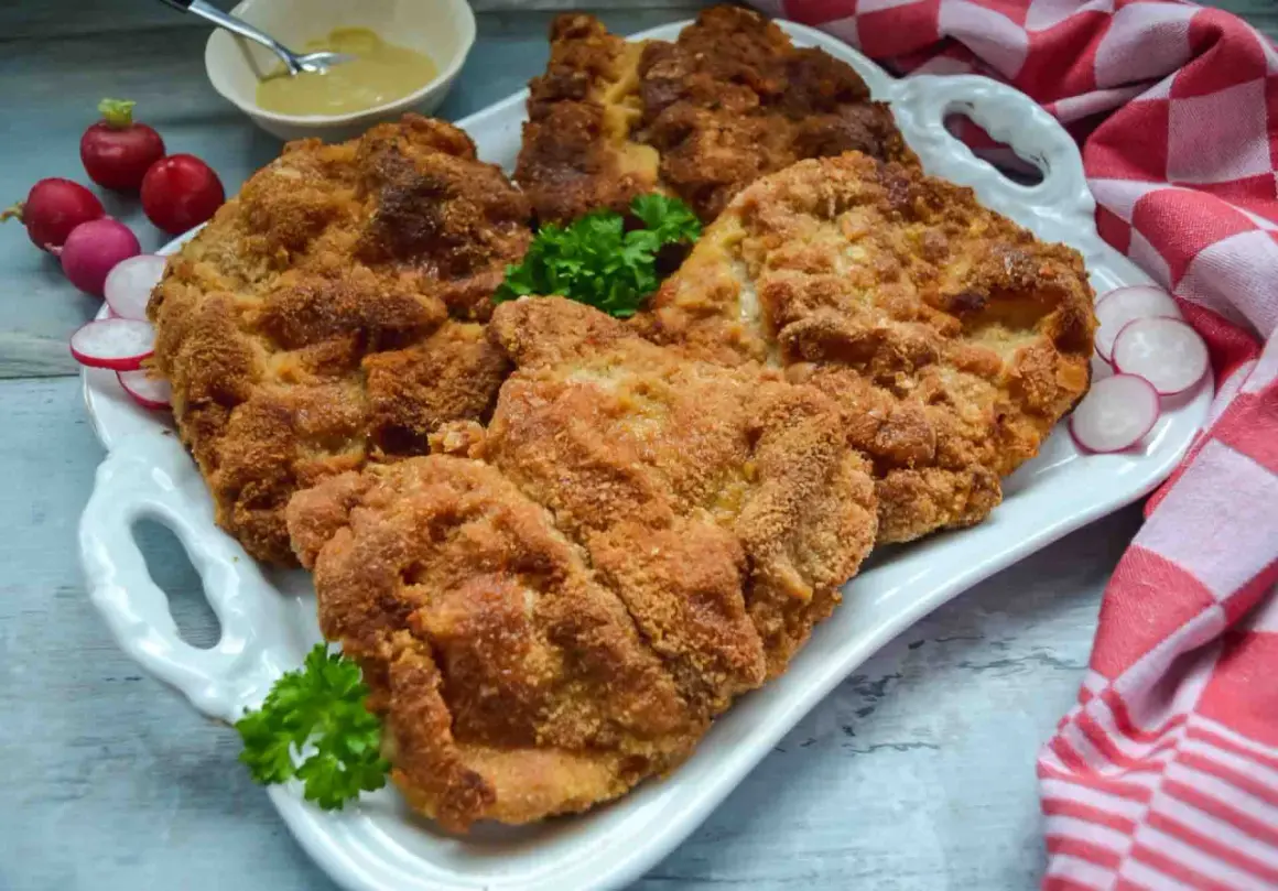Goldbraun paniertes Schnitzel, perfekt zum Schnitzel panieren. Dazu Radieschen, Petersilie und Senf.
