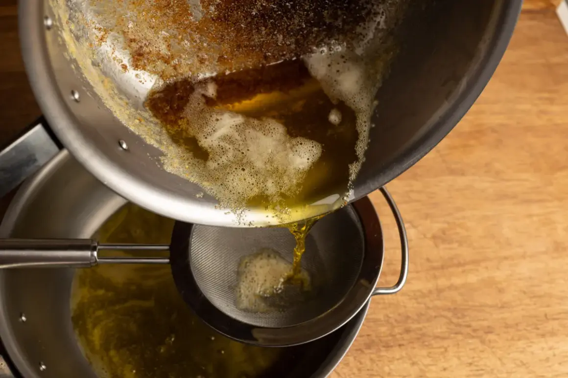 Braunes Butter wird durch ein Sieb gegossen, um die festen Bestandteile zu entfernen.