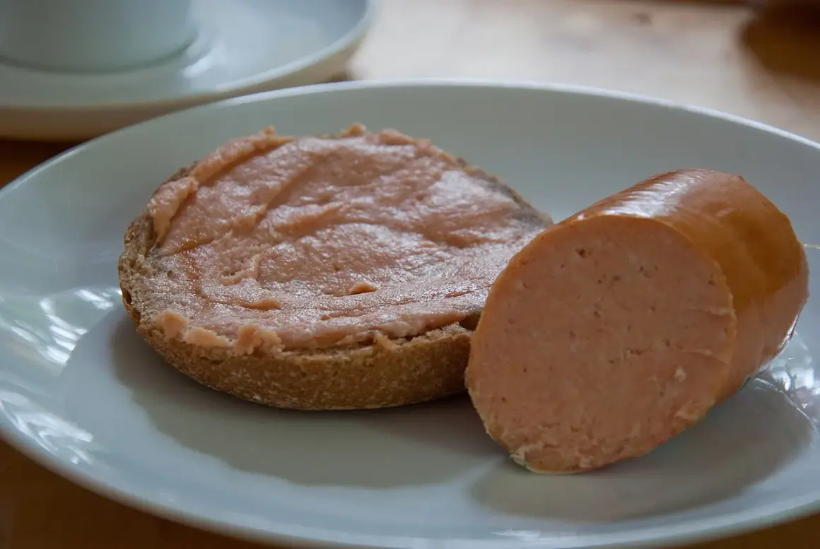 Ein Brötchen mit Teewurst und ein Stück Teewurst daneben. So sieht die beliebte Teewurst aus.