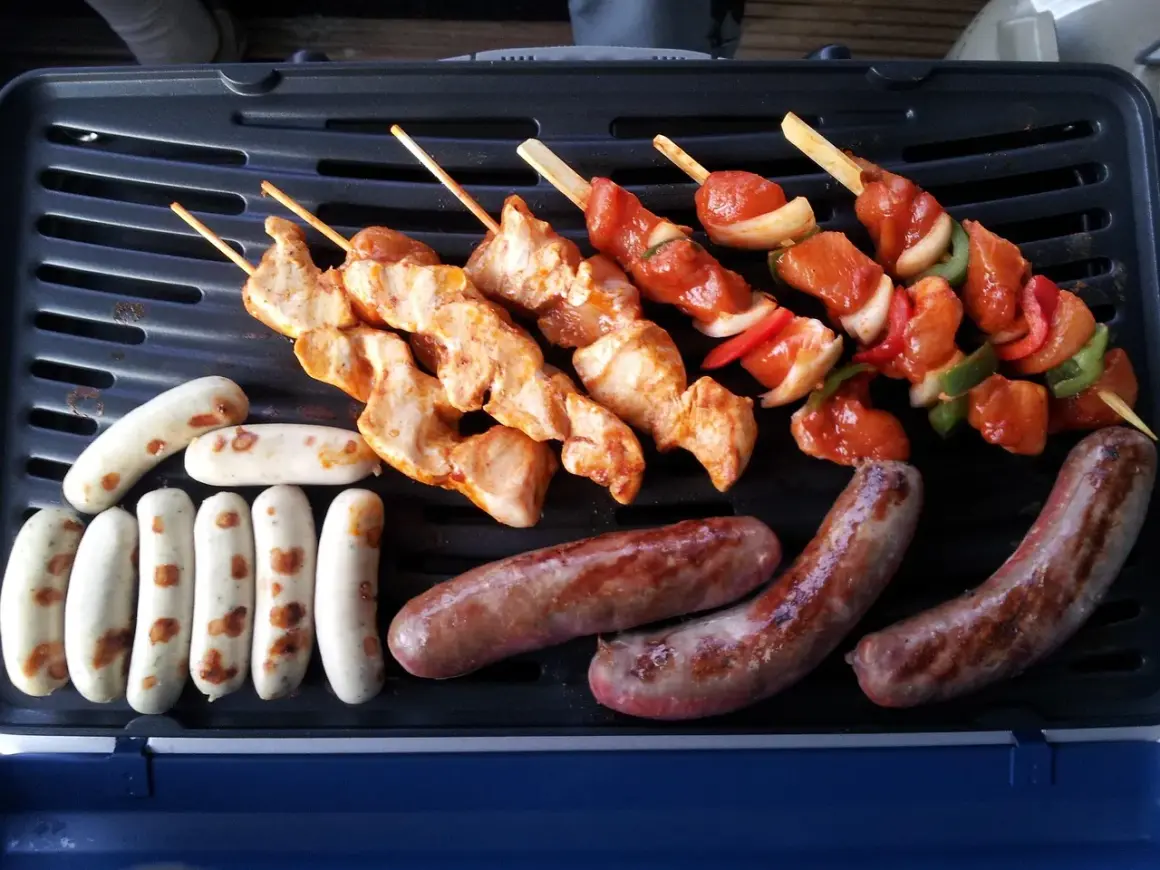 Fleisch auf Gasgrill richtig grillen: Hähnchenspieße und Würstchen brutzeln auf dem Grill.