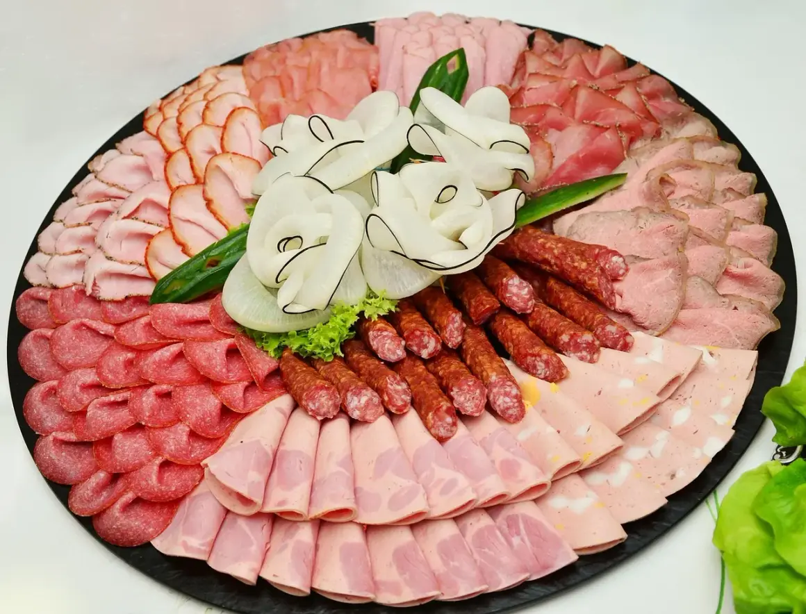 Eine reichhaltige Auswahl an Wurst Sorten, kunstvoll arrangiert auf einer Platte. Verschiedene Schinken-, Salami- und Brühwurst-Varianten laden zum Genuss ein.
