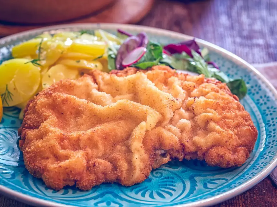 Goldbraunes Wiener Schnitzel mit Kartoffelsalat und frischem Grün. Ein perfektes Wiener Schnitzel Rezept für Genießer.