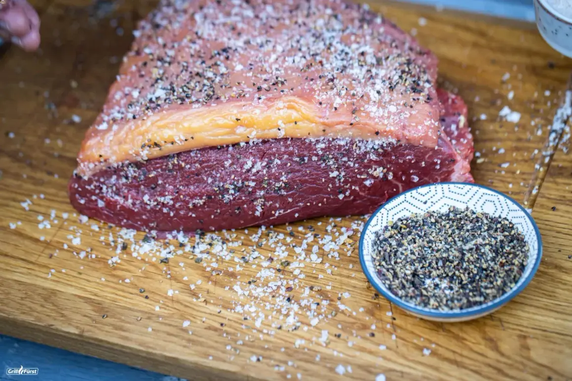 Ein roher Tafelspitz mit Salz und Pfeffer bestreut, bereit für das Tafelspitz grillen. Daneben eine Schale mit Pfefferkörnern.