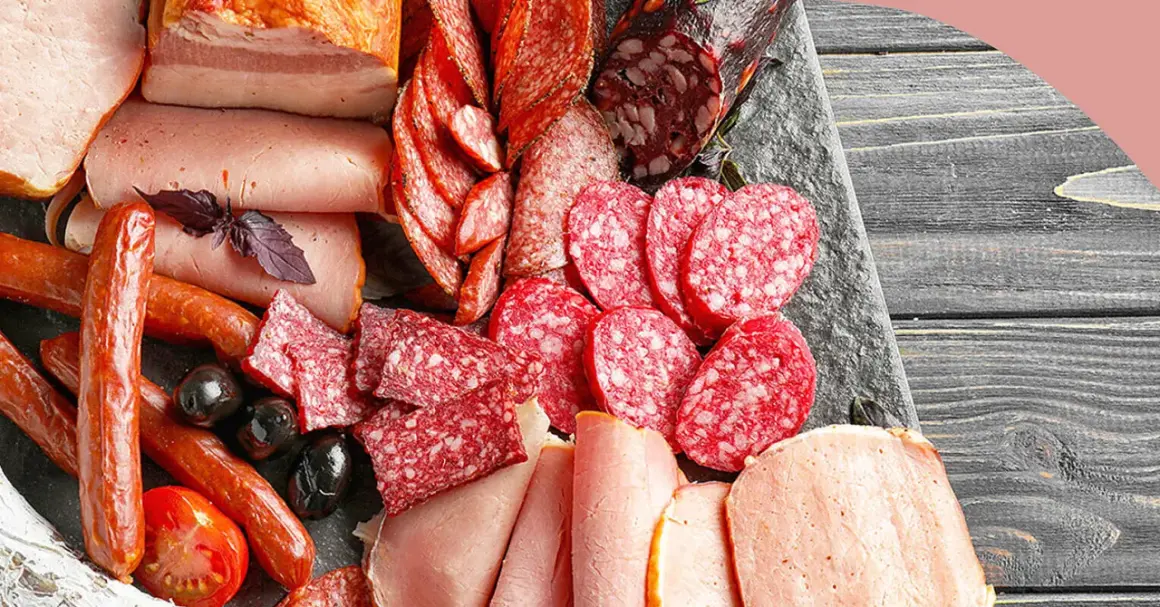 Eine Auswahl an Wurstwaren: Salamischeiben, Kochschinken, Bratwürste und Speck. Die Vielfalt zeigt die **Definition Wurst** in ihrer ganzen Pracht.