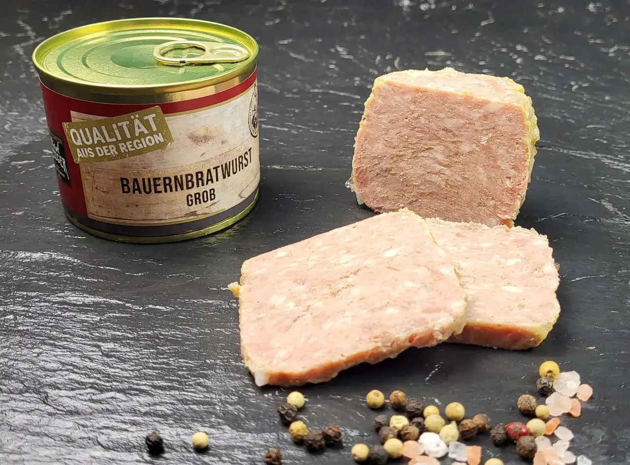 Dose Bauernbratwurst grob, aufgeschnitten, mit Pfefferkörnern und rosa Salz. Die Zutaten für diese herzhafte Wurst sind traditionell.