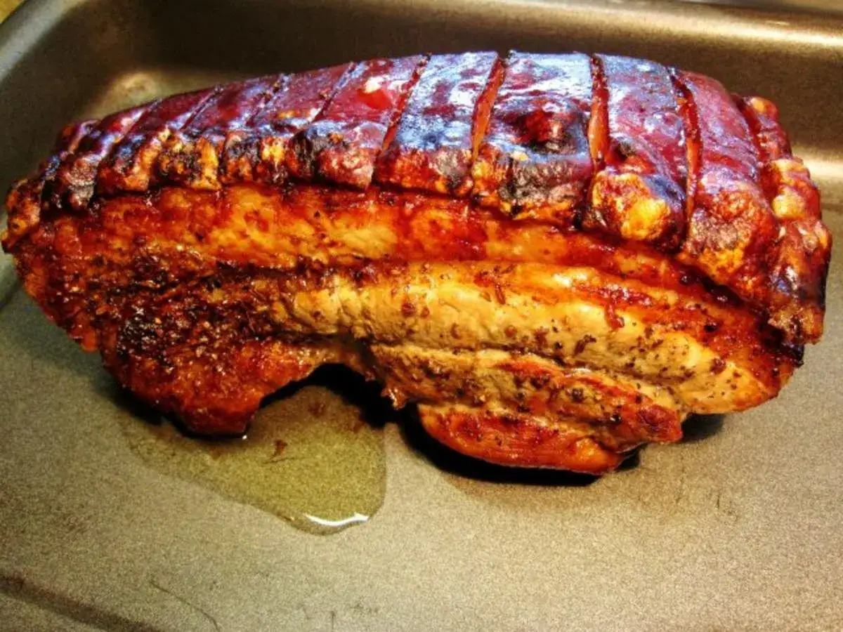 Perfekt gegrillter Schweinebauch mit knuspriger Schwarte liegt in einer Bratpfanne. Der Duft von gebratenem Fleisch liegt in der Luft.