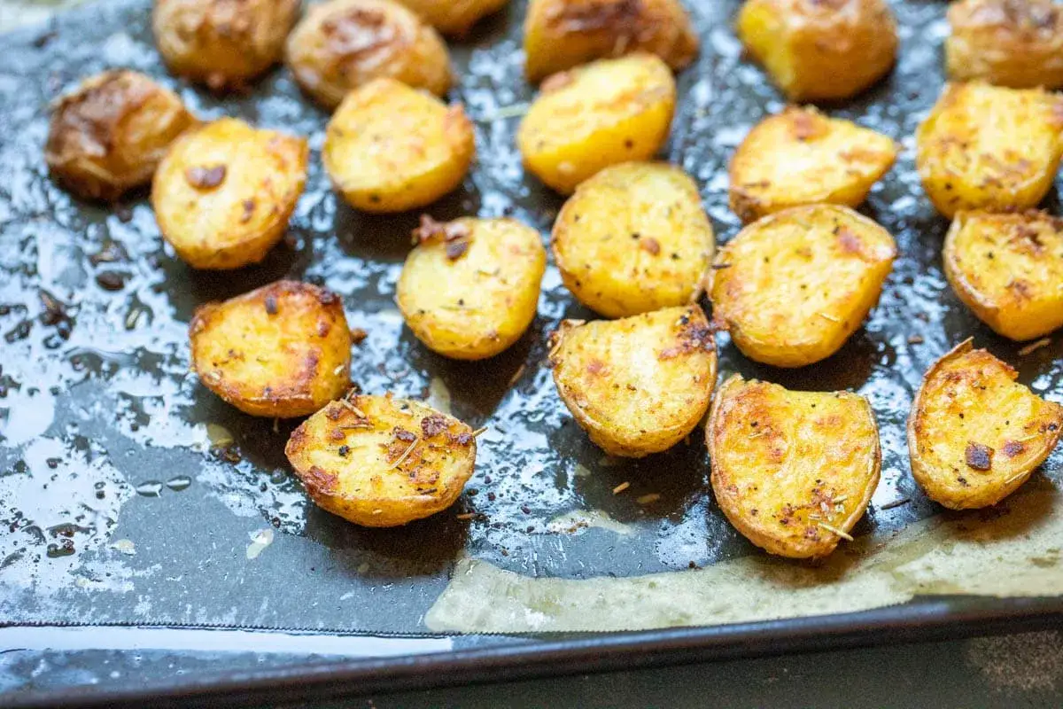 Goldbraune, knusprige Kartoffelspalten, perfekt f&uuml;r ein einfaches Ofenkartoffeln Rezept. Mit Kr&auml;utern und Gew&uuml;rzen verfeinert.