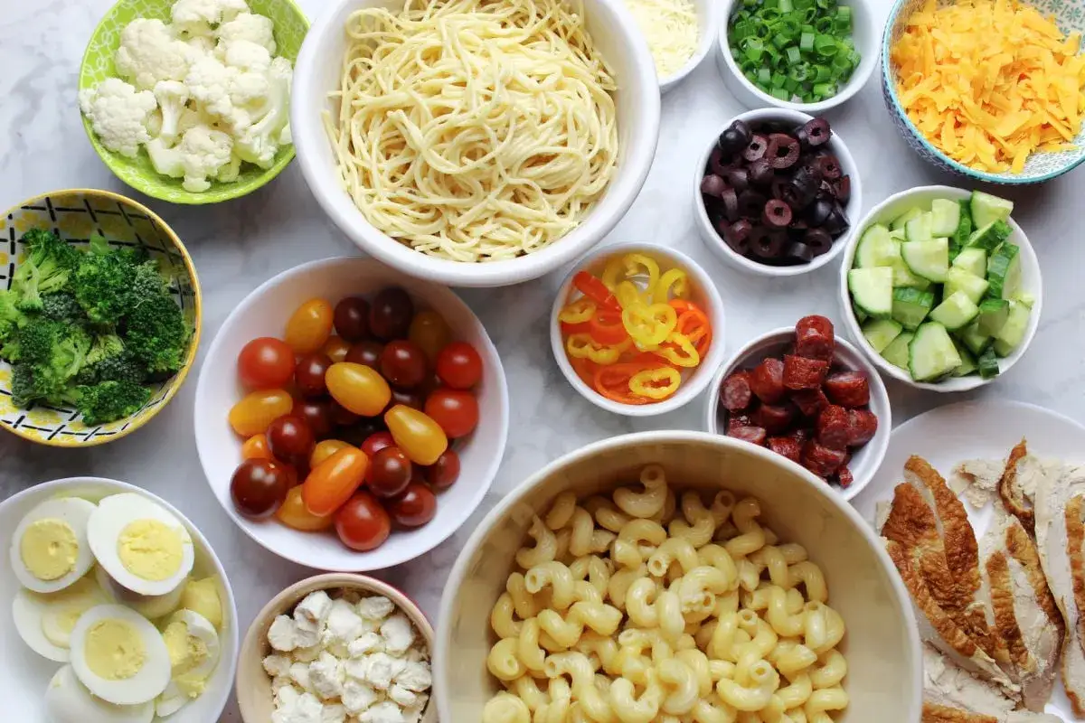 Bunte Zutaten für einen leckeren Nudelsalat: Pasta, Gemüse, Eier, Käse und Wurst. Was passt zu Nudelsalat? Alles hier!