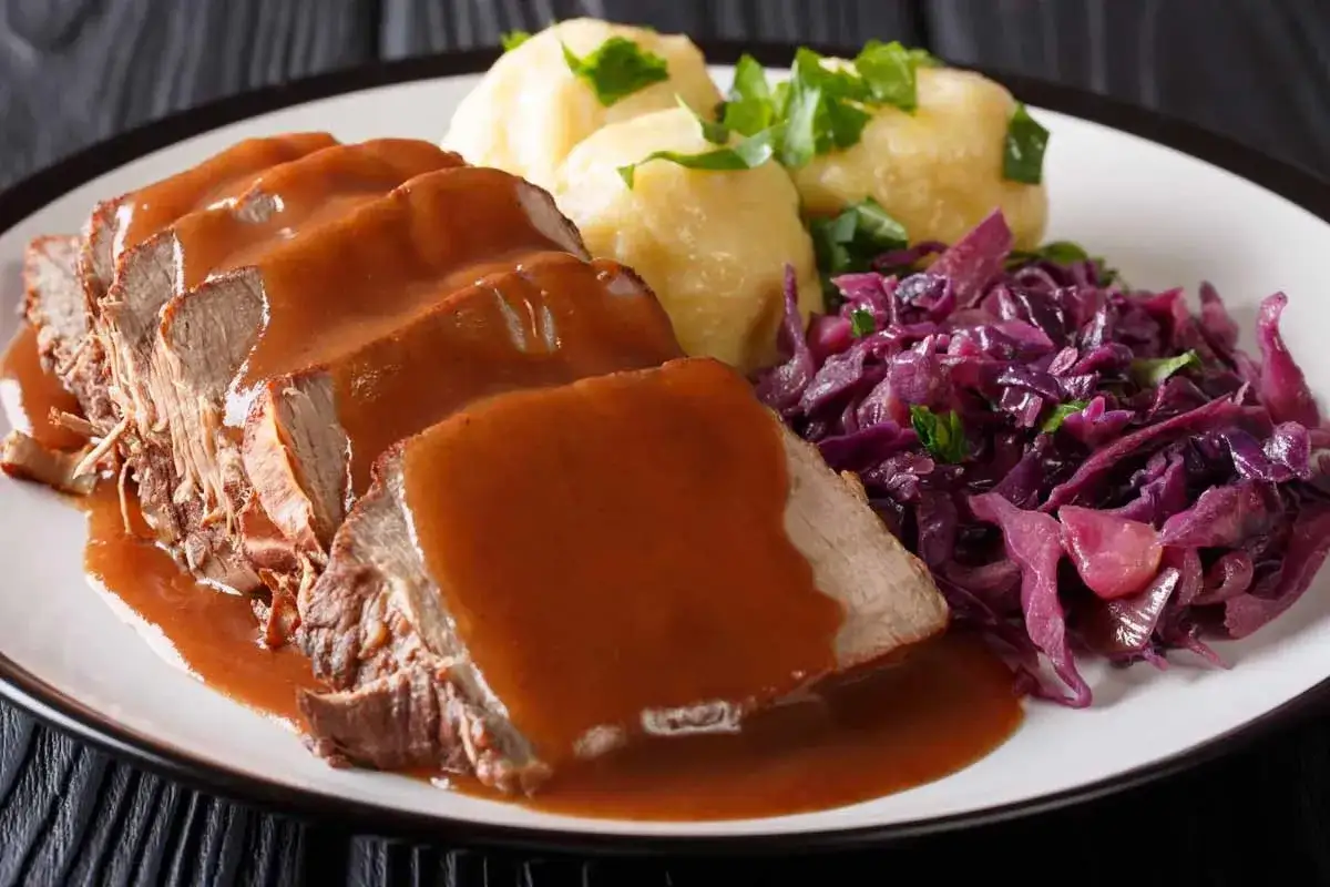 Saftiger Sauerbraten mit Klößen und Rotkohl, ein klassisches Gericht, das nach diesem Rezept gelingt.