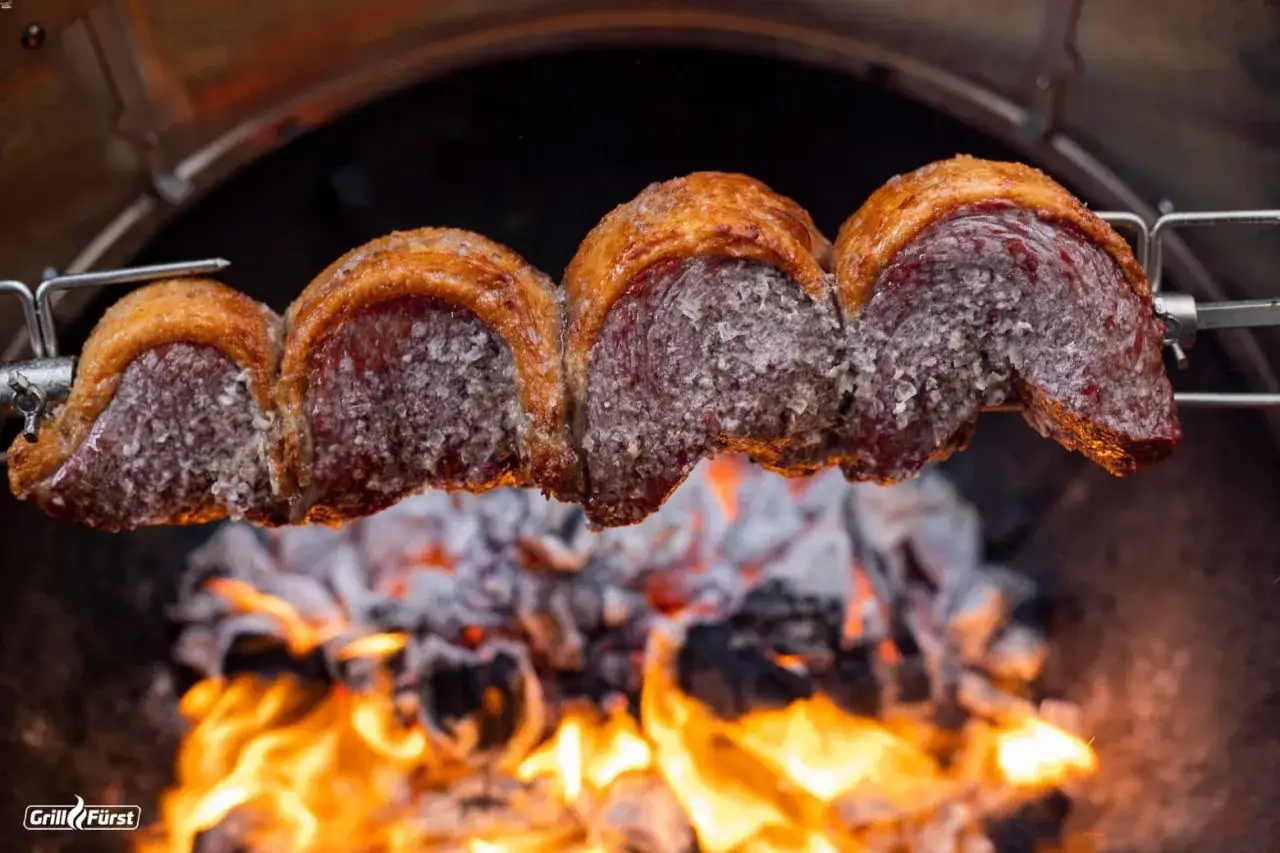 Saftiger Tafelspitz wird am Spieß über glühender Kohle gegrillt. Die Kruste bräunt, während das Fleisch langsam gart.