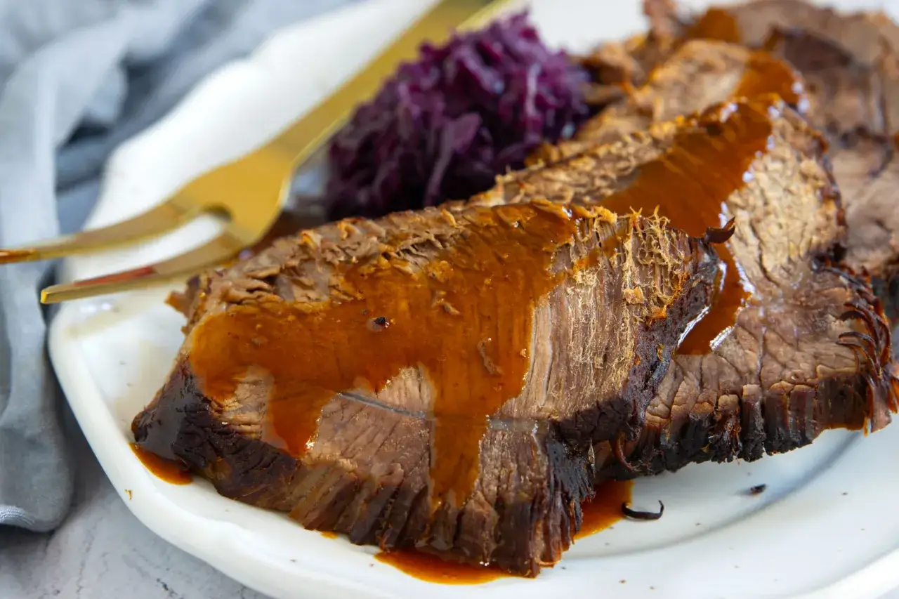 Saftiger Stracotto di manzo mit dunkler Sauce und Rotkohl auf einem Teller.
