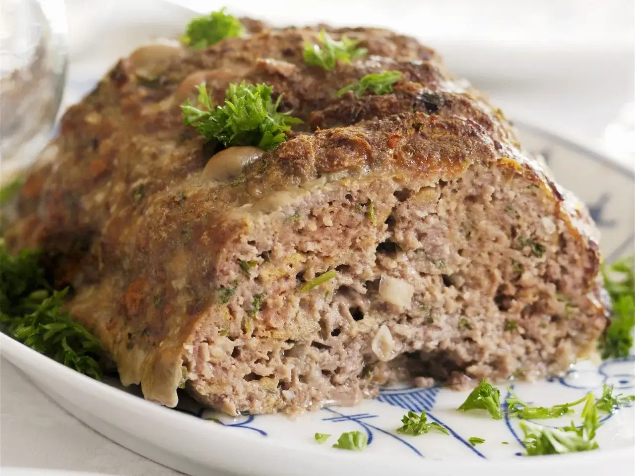 Saftiges gehacktes Rindfleisch, mit Kräutern und Pilzen verfeinert, auf einem Teller mit Petersilie garniert.