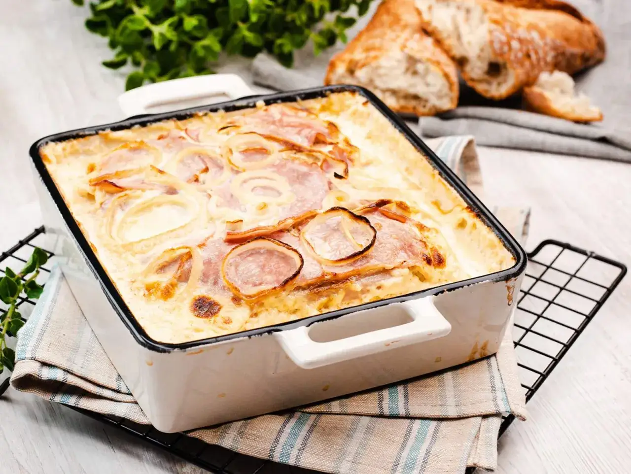 Herzhafte Schnitzelpfanne Landfrauen Art, überbacken mit Zwiebeln und Schinken. Dazu knuspriges Baguette.