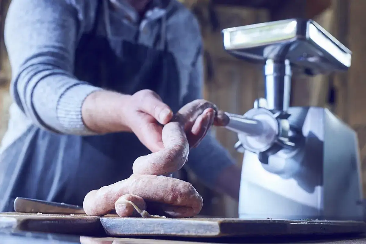 Fleischwolf hilft beim wurst herstellen. Frische Bratwürste werden von Hand geformt.