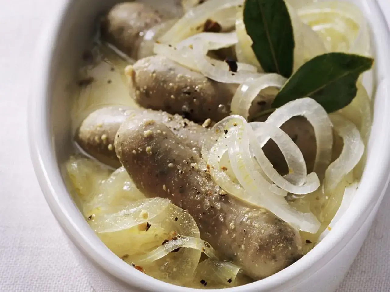 Herzhafte blaue Zipfel in einer cremigen Zwiebelsauce, garniert mit Lorbeerbl&auml;ttern.