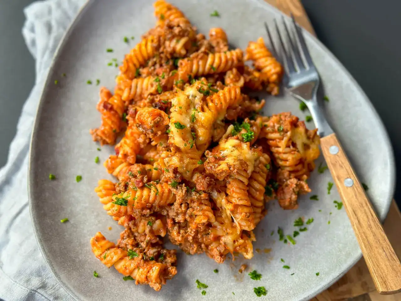 Ein Teller mit fusilli-Nudeln in einer herzhaften Hackfleischsauce, &uuml;berbacken mit K&auml;se. Ein 