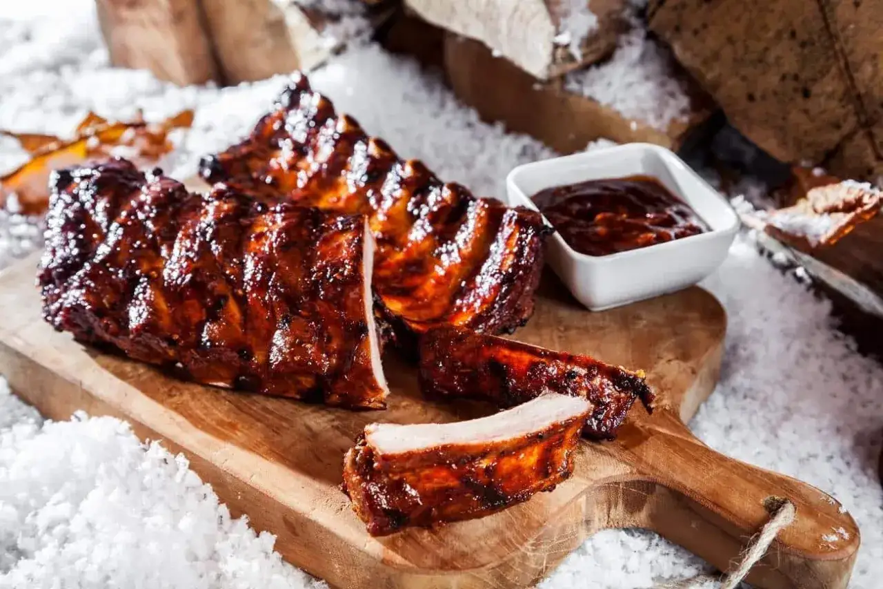 Saftige spareribs im backofen umluft wie lange? Hier sind sie glasiert und bereit zum Genuss, mit einer Schale BBQ-Sauce.