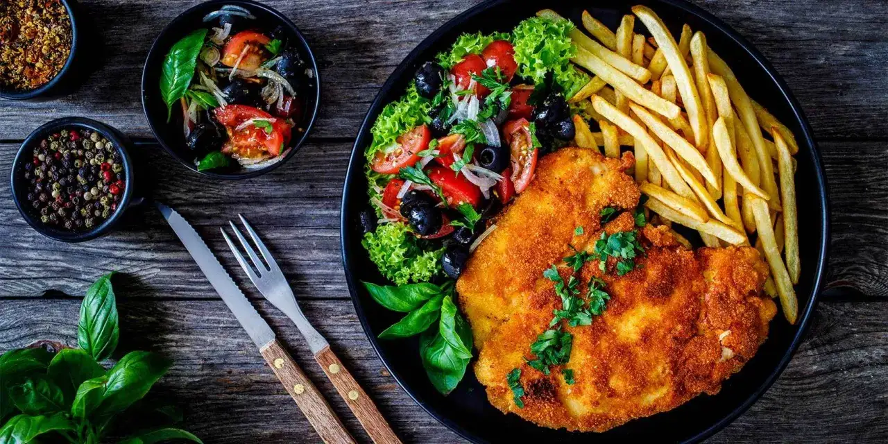 Knuspriges paniertes Schnitzel mit Pommes und Salat. Wie lange paniertes Schnitzel braten? Perfekt goldbraun!