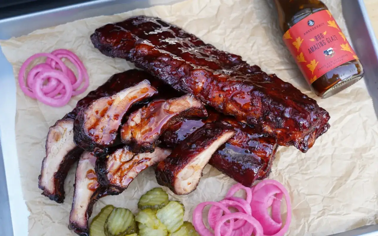Saftige Spareribs vom Grill, glasiert und bereit zum Genießen, mit eingelegten Zwiebeln und Gurken.