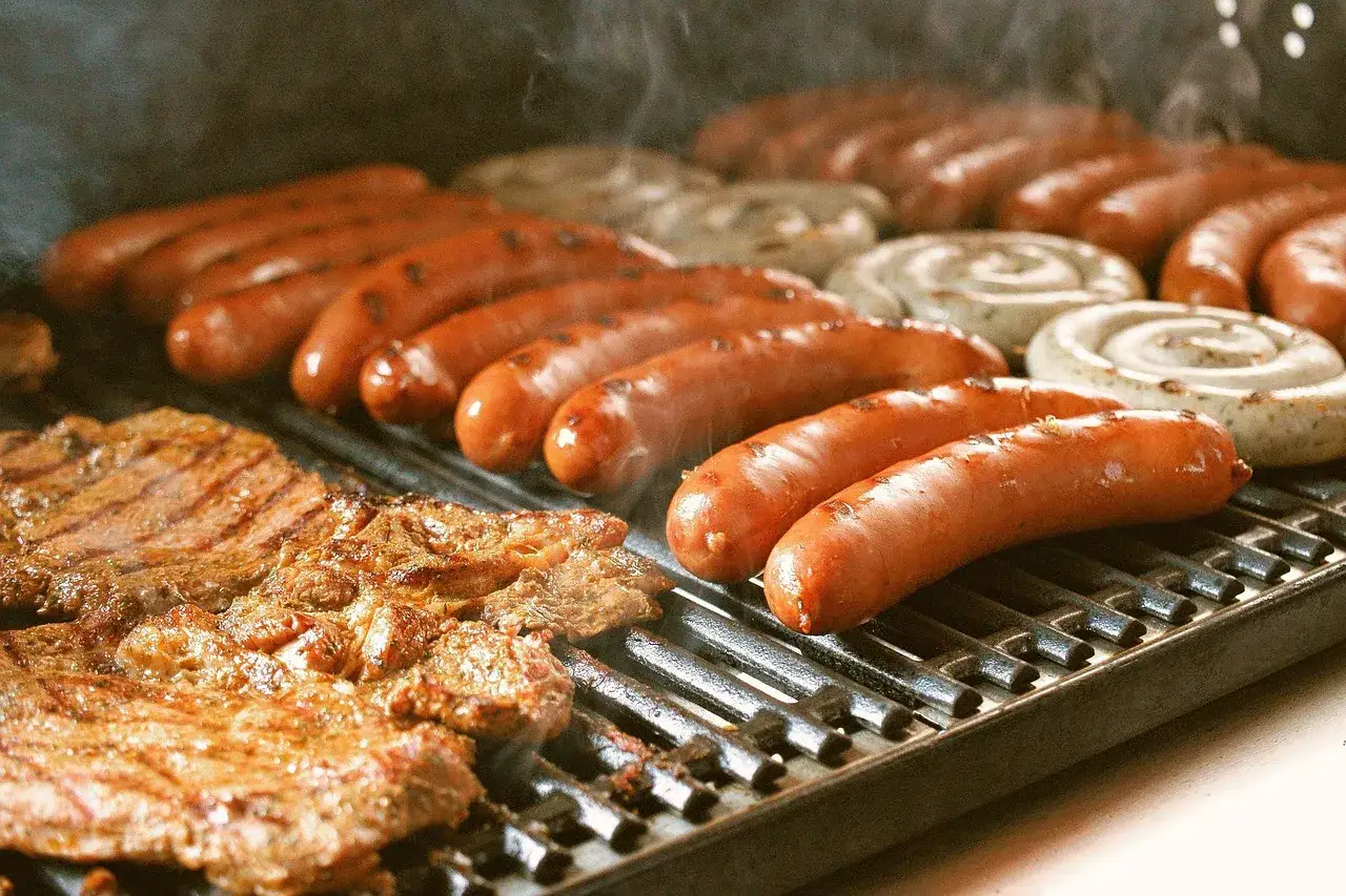 Bratwurst und Steaks brutzeln auf dem Grill. Das Bratwurst Gewicht ist perfekt für den Hunger.