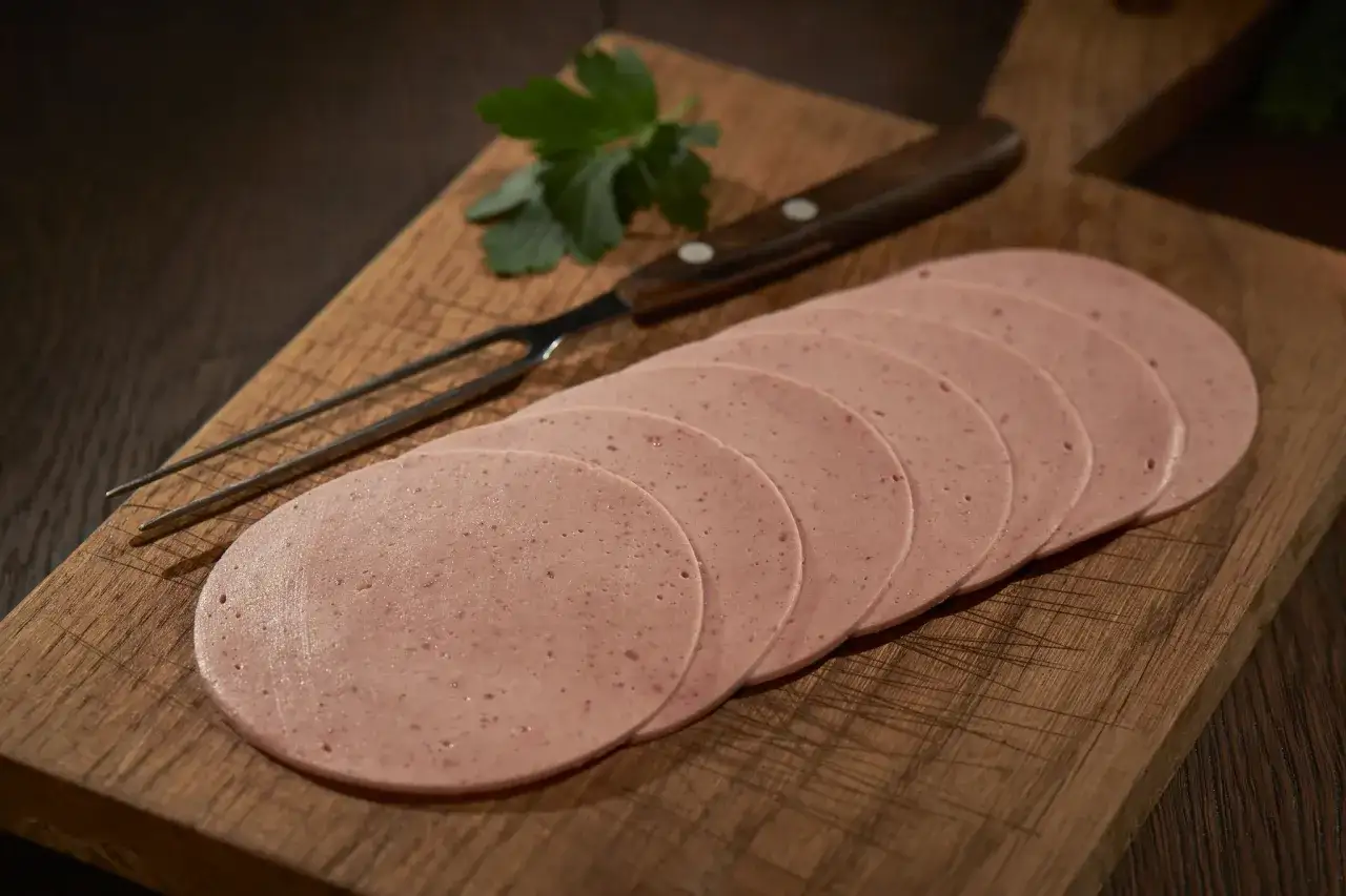 Aufgeschnittene Lyoner und Fleischwurst auf Holzbrett. Der Unterschied ist subtil, aber die Textur verrät es.