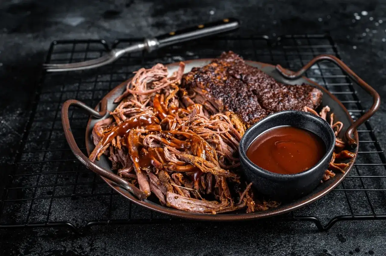 Saftiges pulled pork mit BBQ-Sauce und einem Stück Brisket. Perfekte pulled pork beilagen für ein BBQ-Fest.