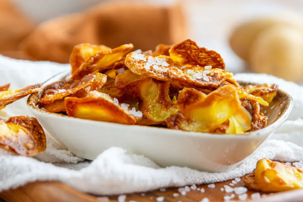 Knusprige, selbstgemachte kartoffelchips mit grobem Meersalz bestreut, serviert in einer Schale. Perfekt zum Knabbern!