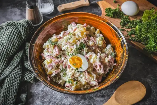 Schüssel mit Kartoffelsalat und Fleischsalat, garniert mit einem halben Ei und Petersilie.