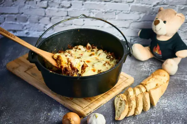 Herzhafter Gyros-Eintopf im Dutch Oven, mit geschmolzenem Käse und Baguette.