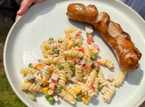 Ein herzhafter Nudelsalat mit Erbsen, Mais und Schinken, dazu eine goldbraune Bratwurst – perfekt, was passt zu Nudelsalat!