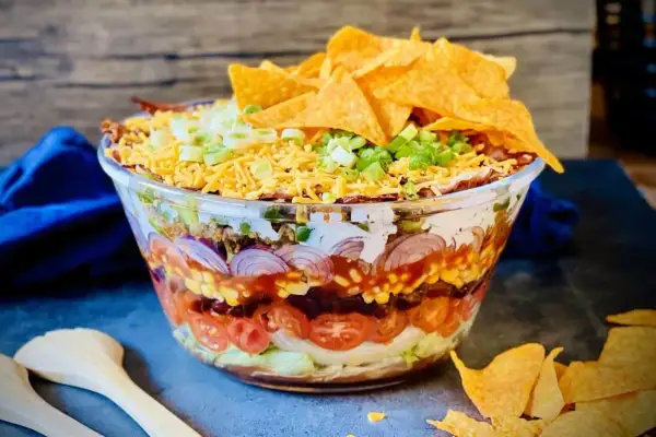 Schichtsalat mit Hackfleisch, Bohnen, Mais, Tomaten, Zwiebeln, Käse und Tortilla-Chips. Perfekt für Taco-Salat Rezepte!
